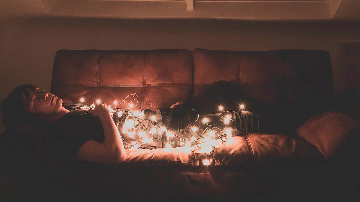 Bertie Scott lay on a brown leather couch with fairy lights draped over him.