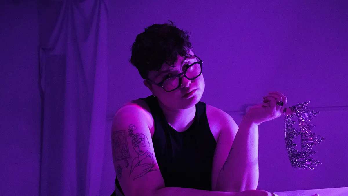Møna in black t-shirt - purple background sitting