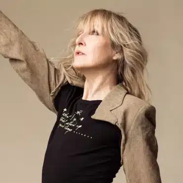 Donna Lewis's hand reaching towards the sky. Wearing a black and goldish beige long-sleeved shirt.