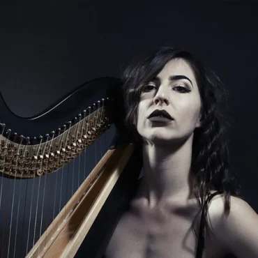 Stephanie Babirak sitting with her harp in a black dress.